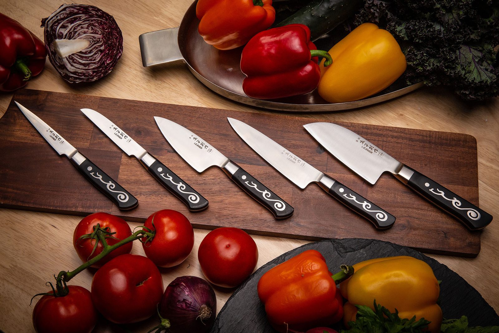 I.O. Shen knife collection laid out on a wooden board